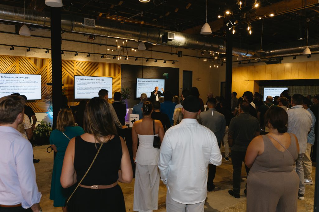 Peter Stringer addressing a full room at the Tampa Digital Mixer, presentation slides on screens behind him