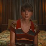 Taylor Swift seated on a bed in a still from the Anti-Hero music video